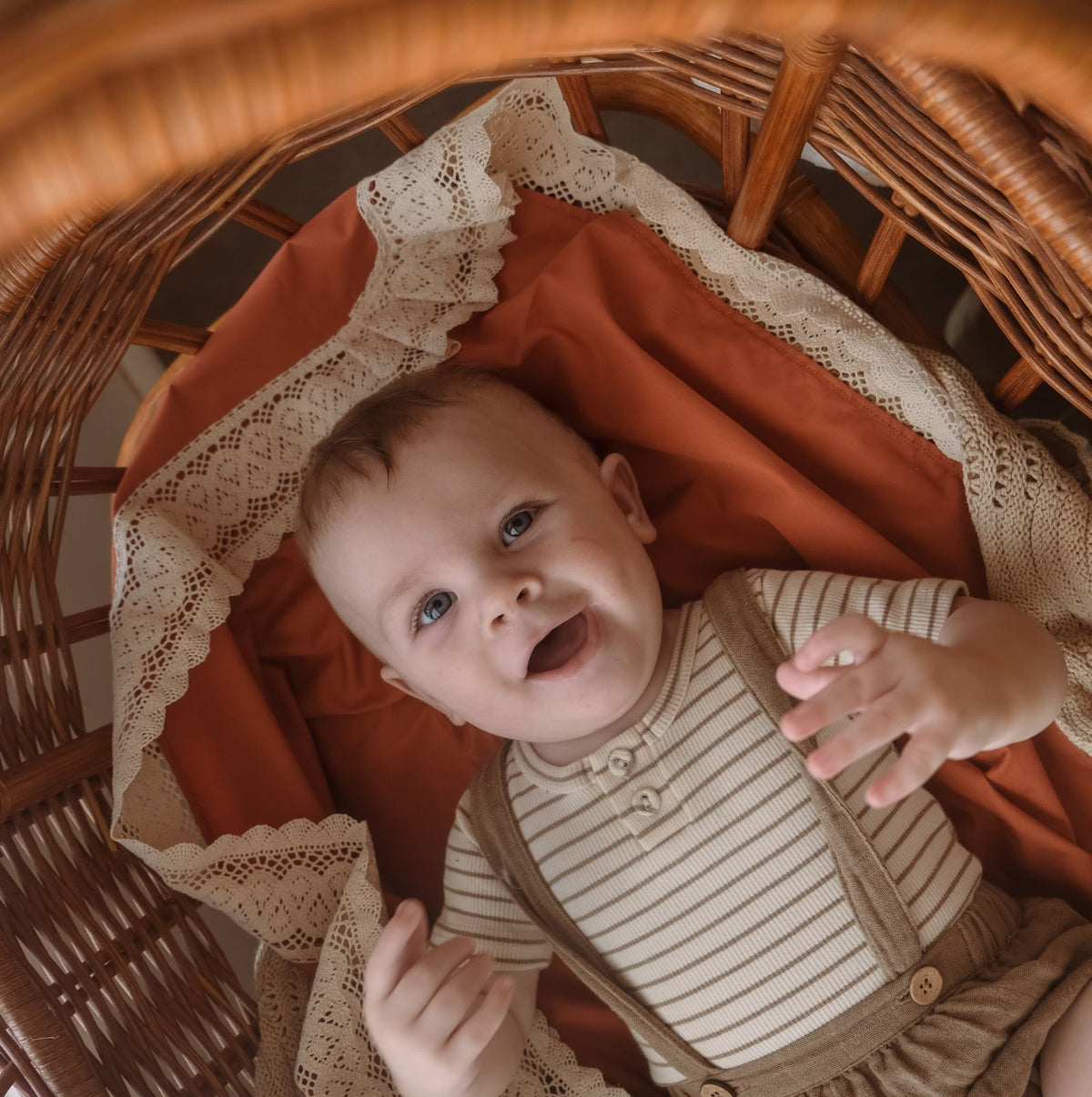 Rust or terracotta baby blanket with wide beige lace trimming for a baby boy nursery 