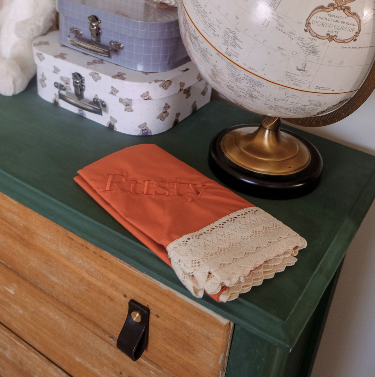 Forest green and vintage world globe in a baby nursery with a rust or terracotta blanket with personalisation